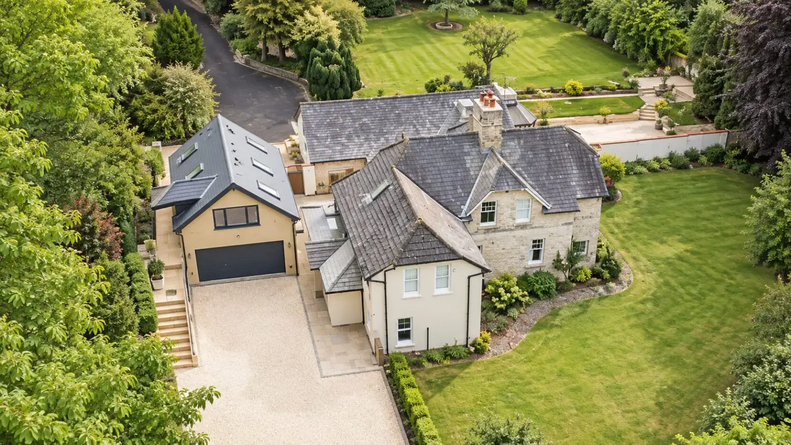 Aerial view of a stone house in Redhill with a new garage extension and gravel driveway