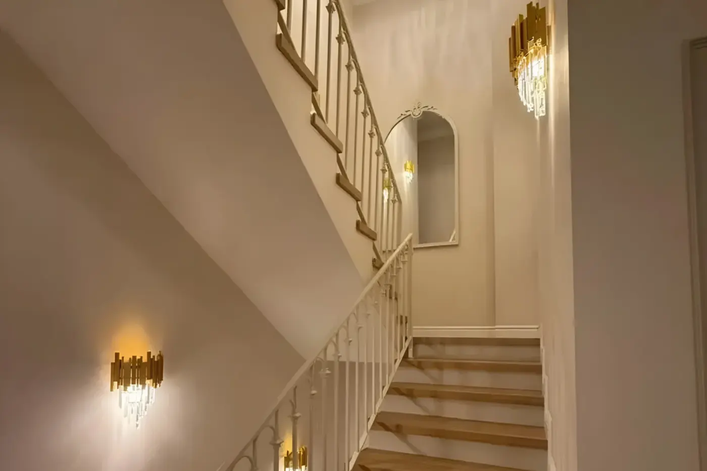 Staircase with brass wall lights and arched niche
